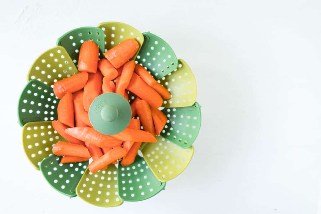 raw carrots in a steamer basket