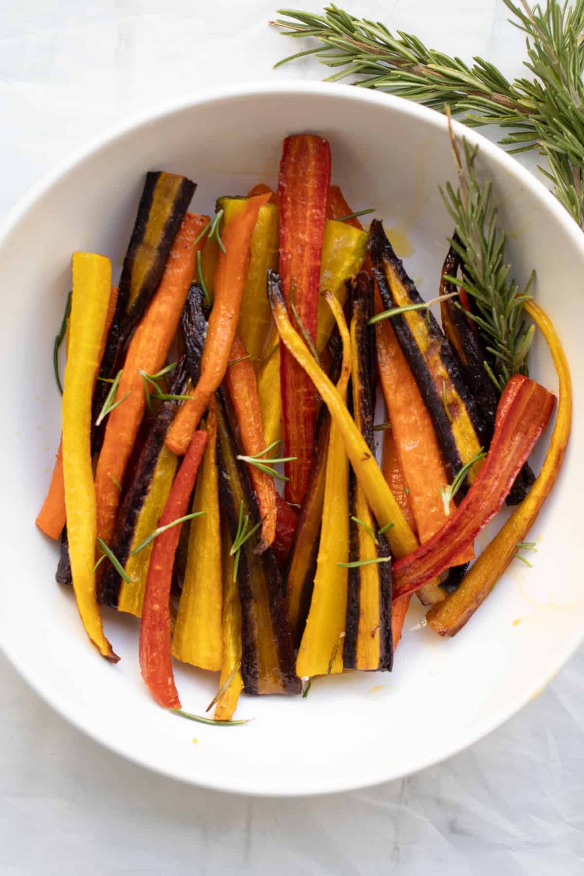 rainbow rosemary roasted carrots in a white serving dish.