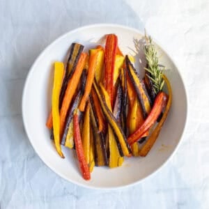 rainbow rosemary roasted carrots in a white serving dish.