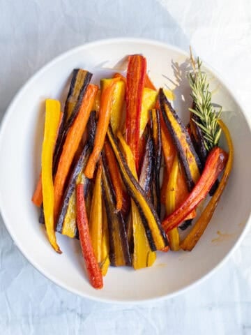 rainbow rosemary roasted carrots in a white serving dish.