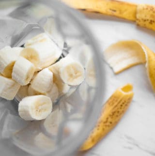 banana chunks in a vitamix blender with an empty banana peel next to it