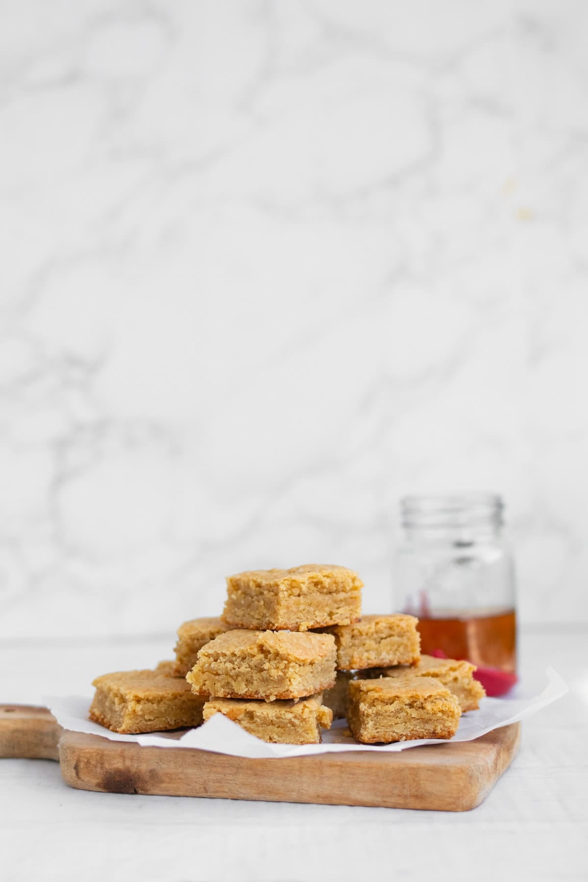 stack of bourbon blondies on a tray with bourbon in background.
