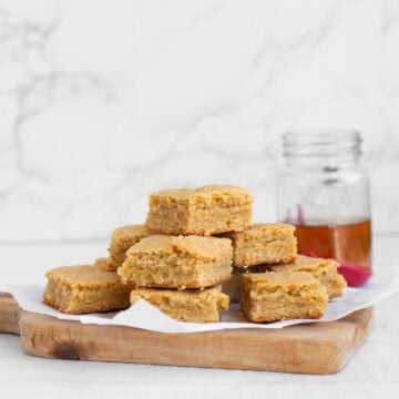 stack of bourbon blondies on a tray with bourbon in background.