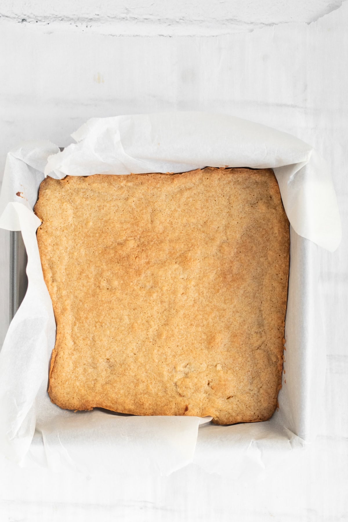 baked bourbon blondies in a parchment lined baking pan.