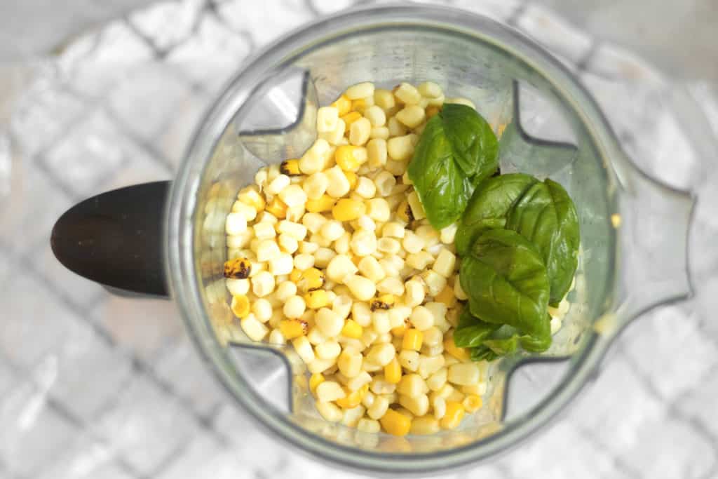 corn and basil in a blender container
