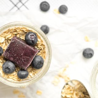 oats in a mason jar with a cube of frozen blueberry puree and fresh blueberries