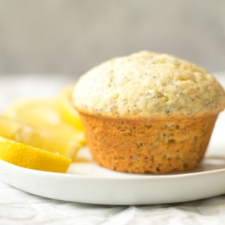 lemon poppy seed muffin on a white plate with lemon slices
