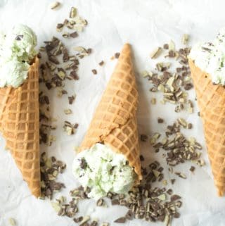 three ice cream cones with no churn mint chocolate chip ice cream inside and andes mint chips scattered around