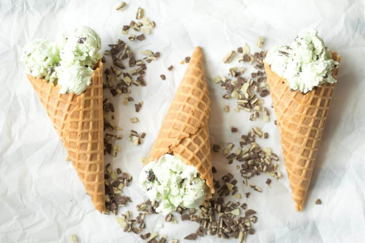 three ice cream cones with no churn mint chocolate chip ice cream inside and andes mint chips scattered around
