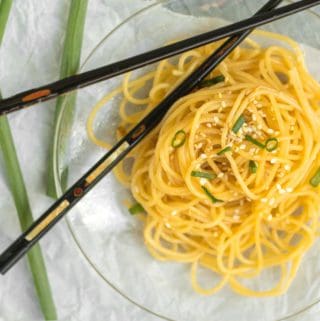 sesame noodles on glass plate with black chopsticks