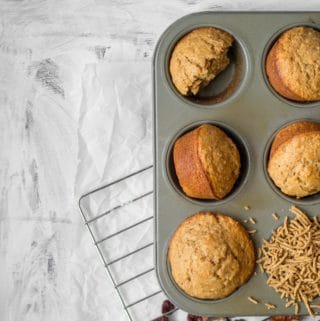 all bran muffins in a muffin tin with one filled with cereal on a cooling rack