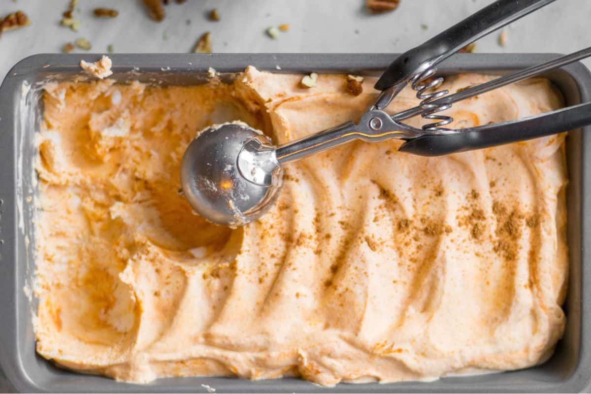 ice cream scoop scooping pumpkin ice cream from a loaf pan.