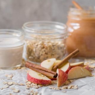 jars of milk, oats and applesauce behind a pile of sliced apples