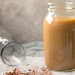 jar of iced coffee with milk, next to a tipped over empty glass milk container