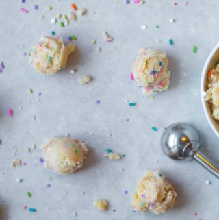 edible sugar cookie dough with sprinkles in a bowl and in balls with a small cookie scoop