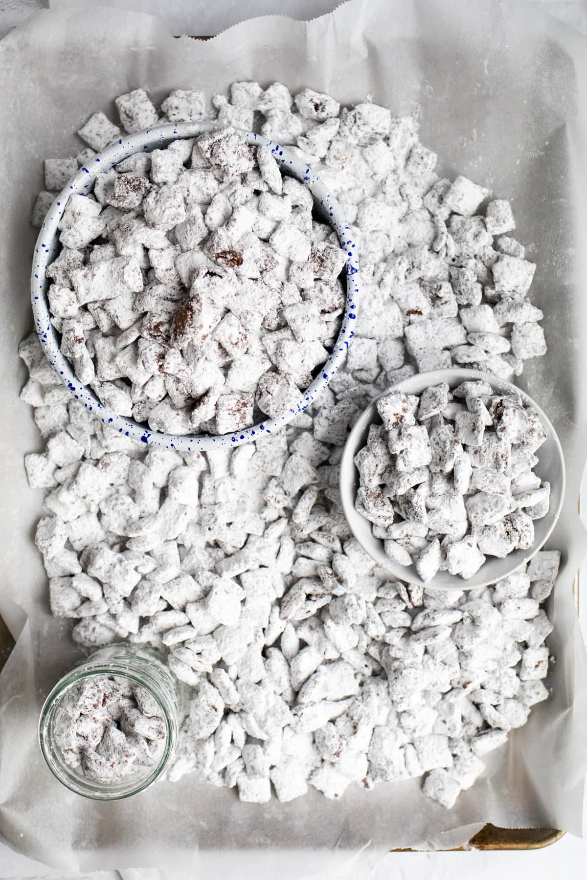 serving bowls of varying size with puppy chow on a sheet tray.