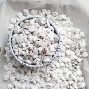 a bowl of puppy chow on a sheet pan covered in muddy buddies.