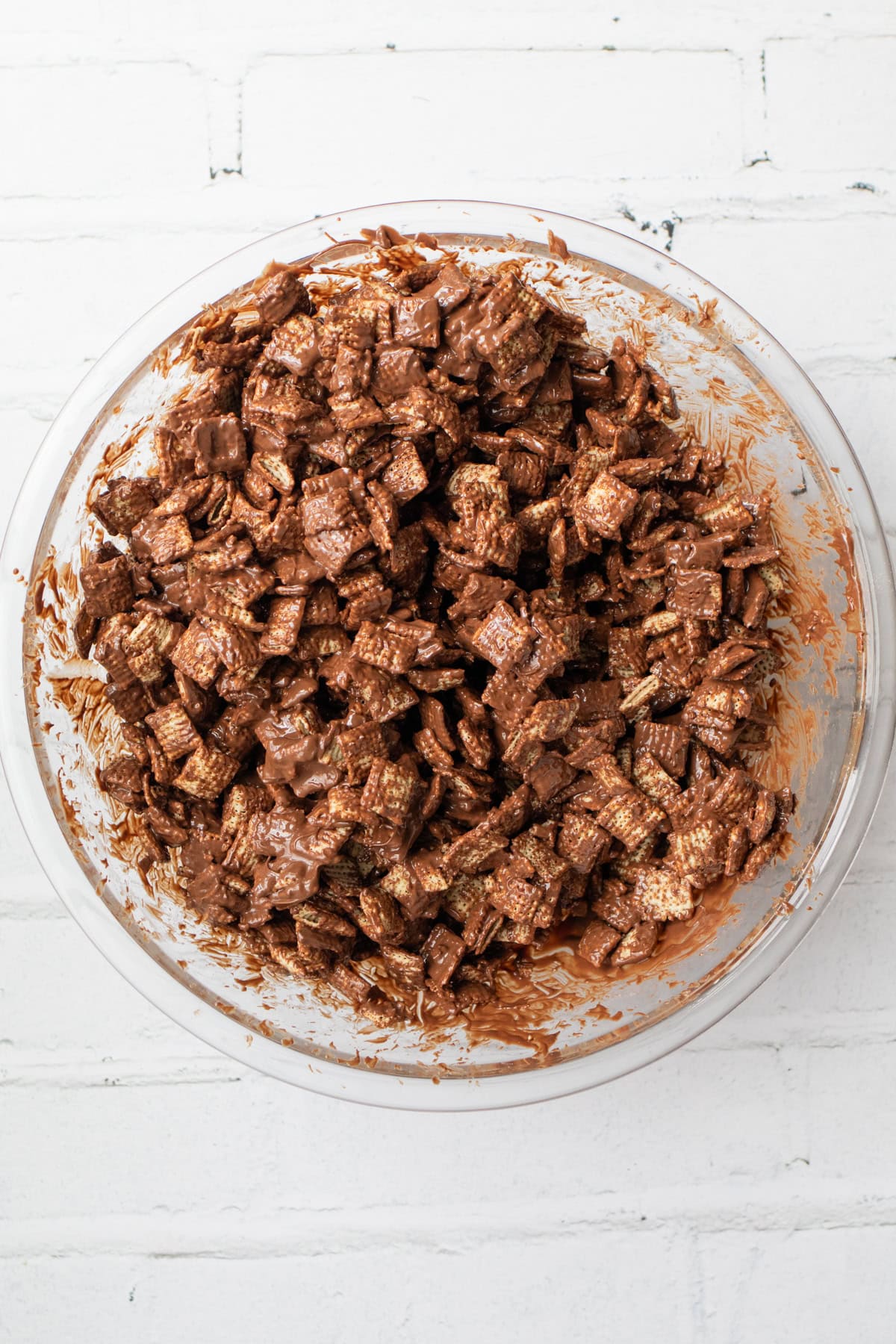 chex cereal mixed with melted chocolate and peanut butter in a glass bowl.