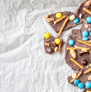 chocolate bark with m&ms, pretzels and salted peanuts on parchment paper