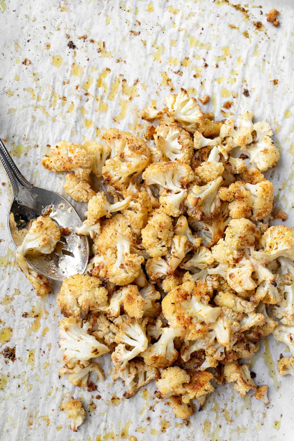 roasted cauliflower on a baking sheet with a serving spoon.