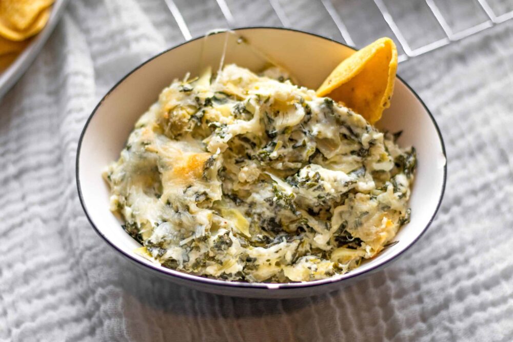bowl of spinach artichoke dip with a corn chip
