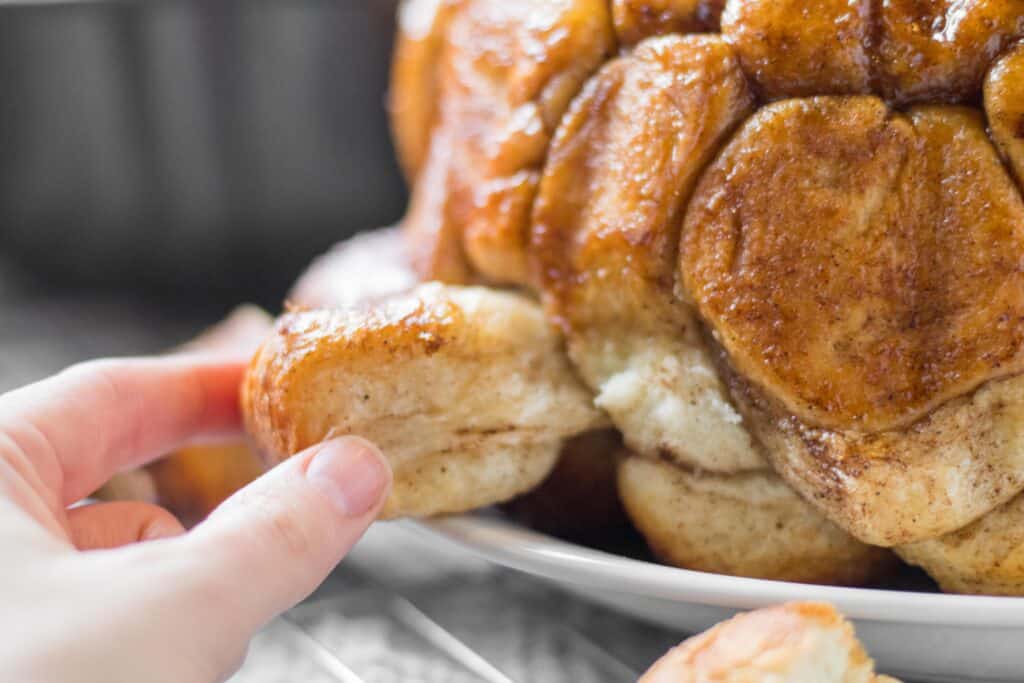 hand pulling a piece of monkey bread out of the whole