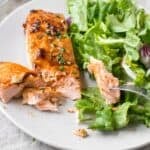 salmon cut into with a fork and salad