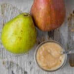 red and green pear next to small container of pear puree