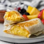 cheesy breakfast burrito on a plate with fruit and salsa