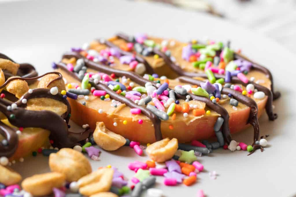 apple donut with sprinkles chocolate and nuts on the side
