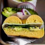 an avocado bagel sandwich sliced in half.