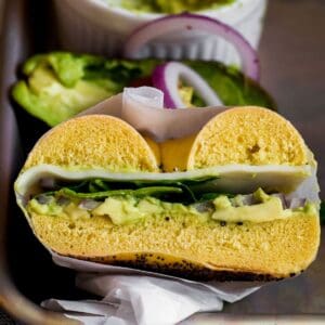 an avocado bagel sandwich sliced in half.