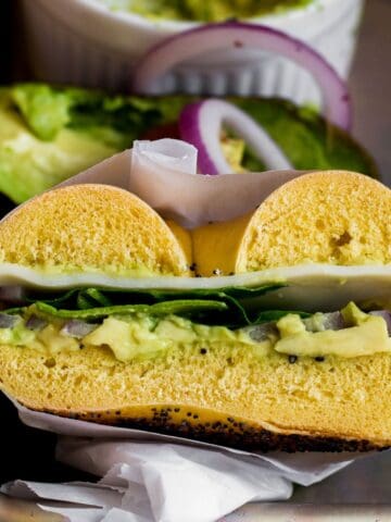 an avocado bagel sandwich sliced in half.