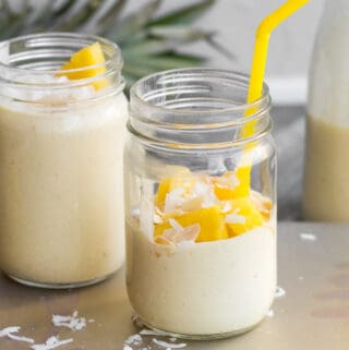 pina colada smoothie in a mason jar with straw and pineapple