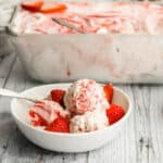 strawberry no churn ice cream in a white bowl with strawberries