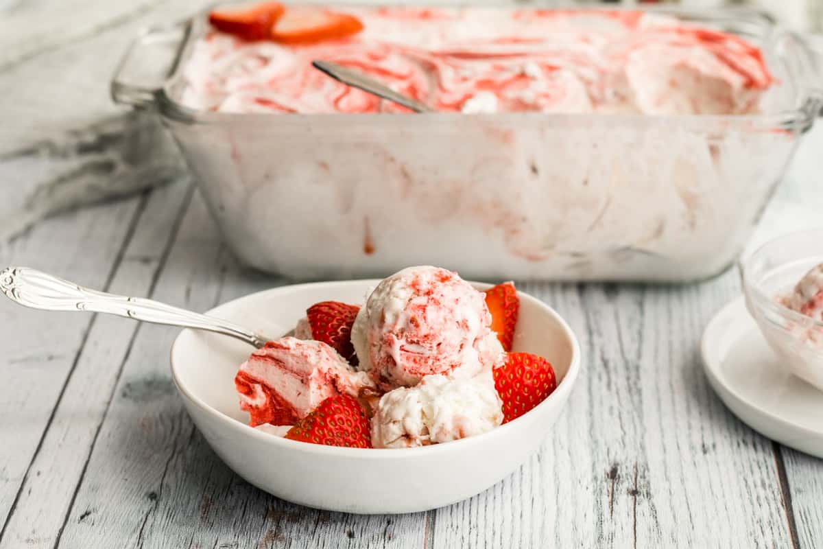 strawberry no churn ice cream in a white bowl with strawberries