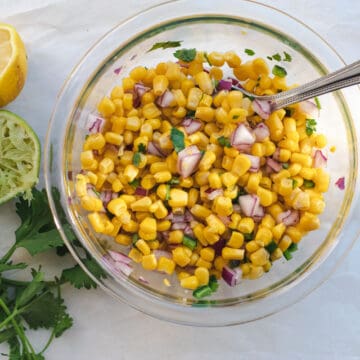 corn salsa in a glass bowl with a spoon to mix