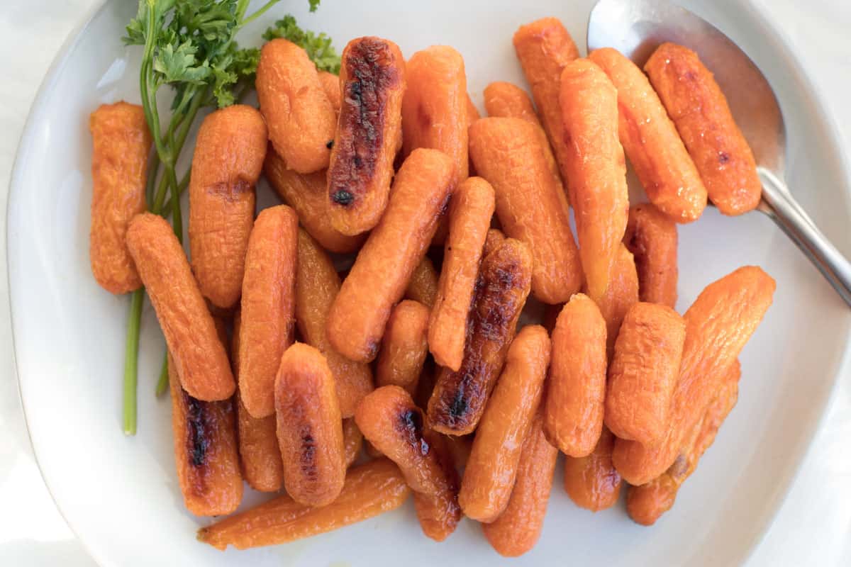 roasted baby carrots on a serving dish with a spoon