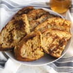 sourdough french toast piled high on a plate with syrup in the background