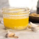 three ingredient garlic butter sauce in a mason jar with cloves of garlic