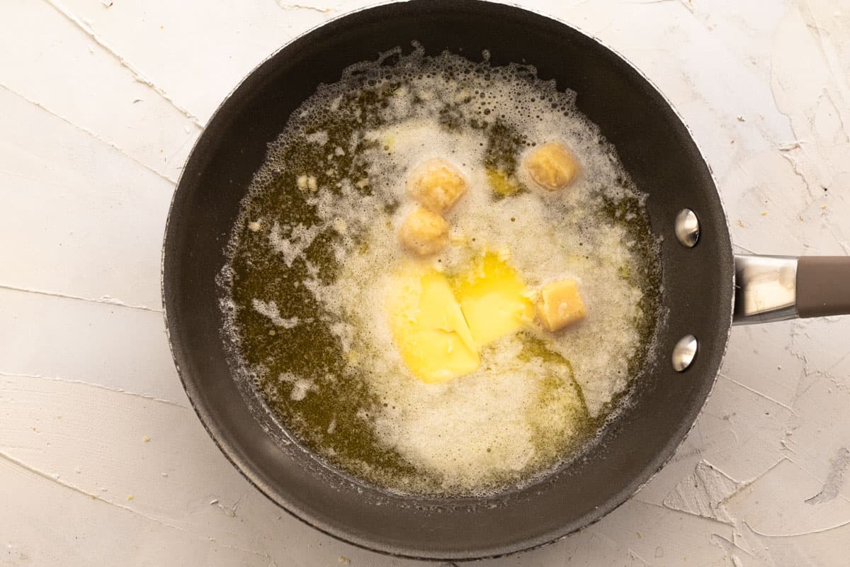 butter and frozen garlic cubes starting to melt in a pan