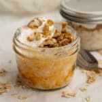 pumpkin overnight oats in a mason jar with whip cream and nuts.