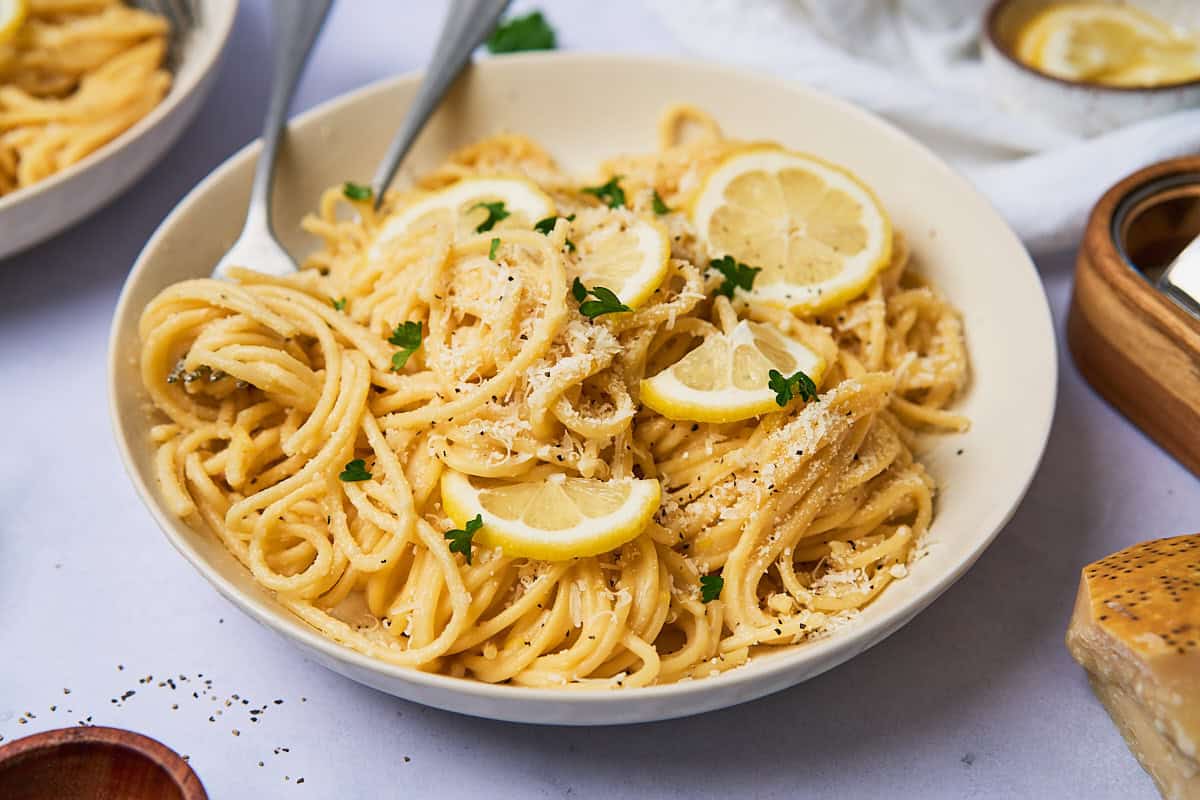 lemon garlic pasta in a serving dish garnished with lemon and parsley.