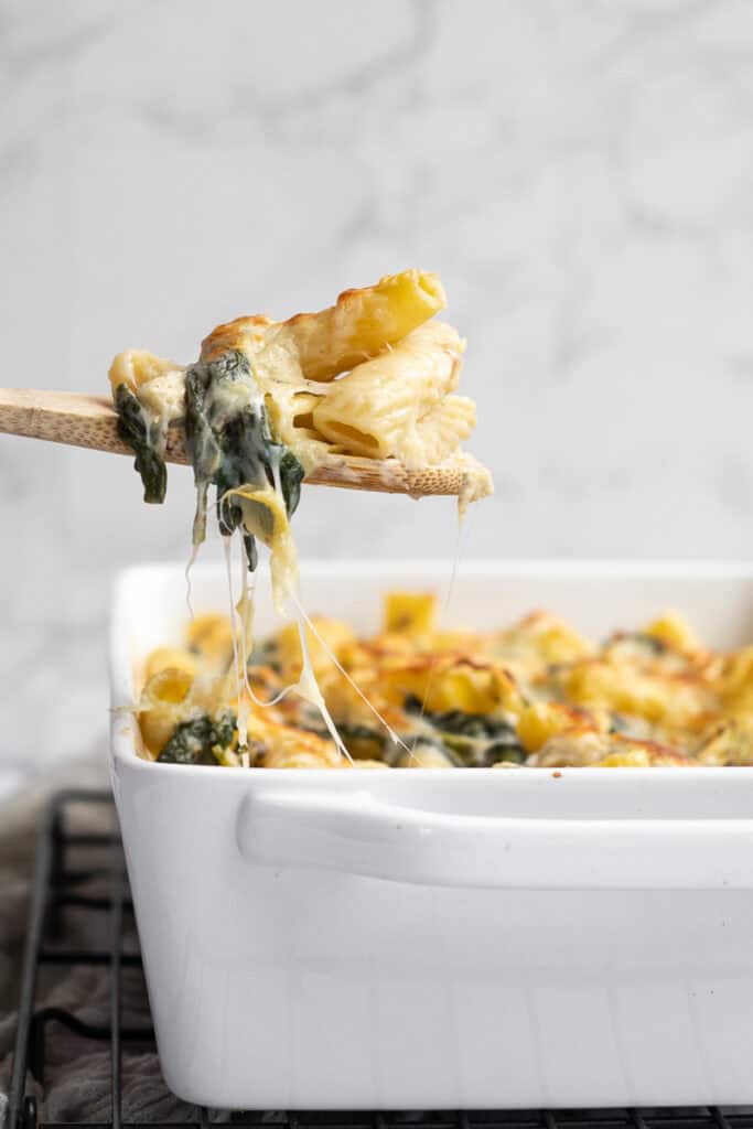 pasta on a wooden serving spoon with a cheese pull.