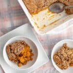 a piece of pumpkin dump cake in a bowl next to the pan