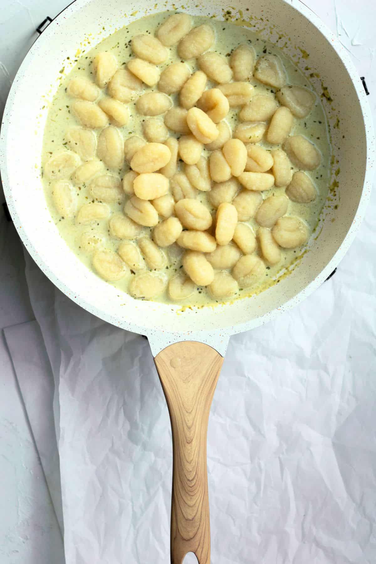 cooked gnocchi in a pan with pesto sauce