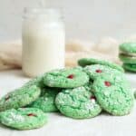 green cookies in pile with a glass of milk behind