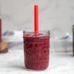cherry smoothie in a mason jar with a red straw
