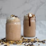 two chocolate smoothies garnished with oats and chocolate chips``