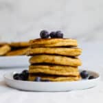 stack of pancakes on a white plate with blueberries on top